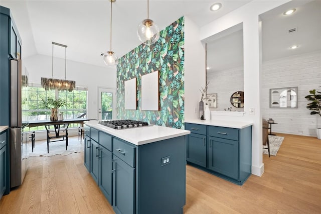 10239 Scull Creek Dr, Austin, TX 78730 - kitchen with stainless steel gas stovetop, light wood finished floors, blue cabinetry, tasteful backsplash, and light countertops