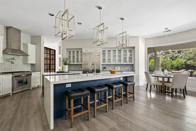 3604 Shady Creek Cv, Austin, TX 78746 - kitchen with stainless steel appliances, wall chimney exhaust hood, backsplash, a chandelier, and dark wood-type flooring