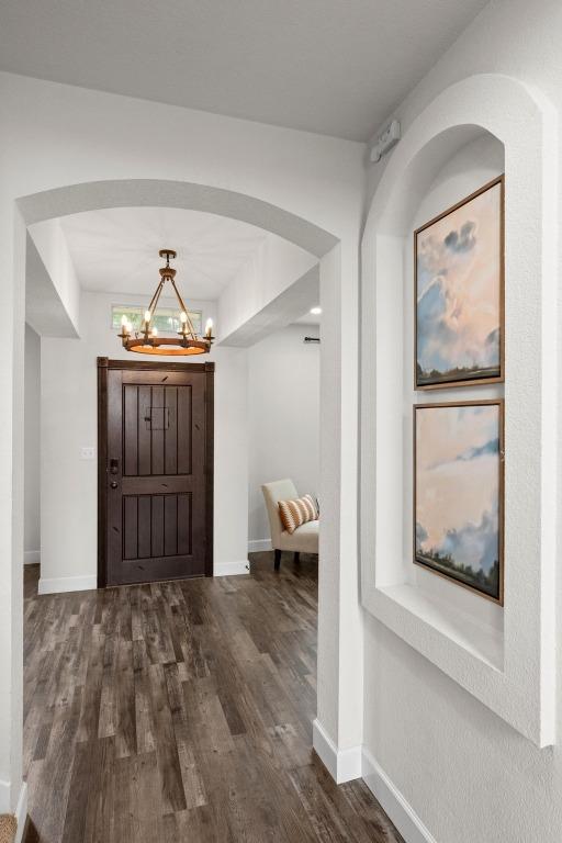 122 Retama Dr, Georgetown, TX 78626 - foyer featuring a chandelier, dark wood-style flooring, baseboards, and arched walkways