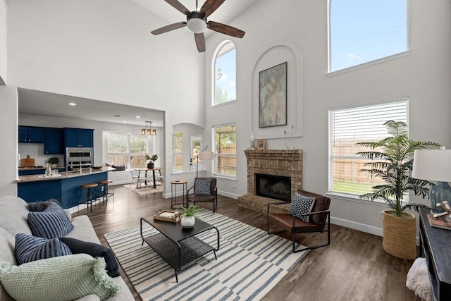 122 Retama Dr, Georgetown, TX 78626 - living area with a towering ceiling, a brick fireplace, ceiling fan, dark wood-type flooring, and baseboards