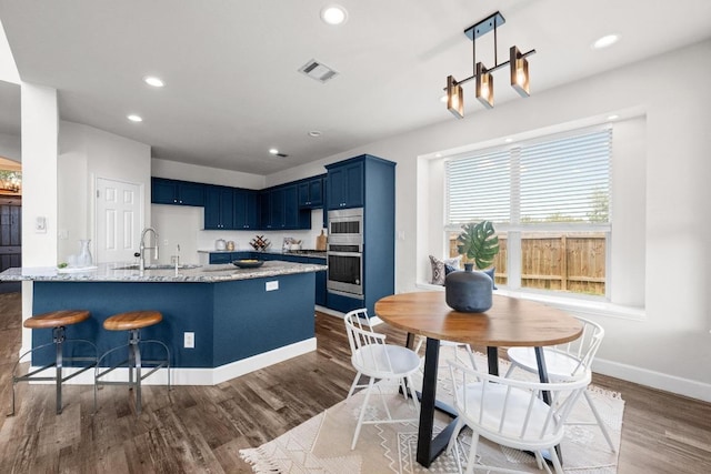 122 Retama Dr, Georgetown, TX 78626 - kitchen featuring blue cabinetry, dark wood-style floors, baseboards, light stone countertops, and a sink