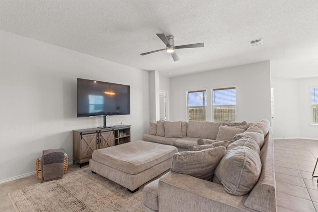 609 Ibis Falls Loop, Jarrell, TX 76537 - living area featuring a ceiling fan, plenty of natural light, a textured ceiling, light tile patterned floors, and baseboards