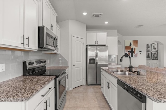 609 Ibis Falls Loop, Jarrell, TX 76537 - kitchen featuring stainless steel appliances, a sink, arched walkways, a kitchen island with sink, and white cabinetry