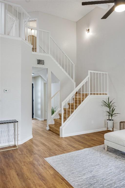 12910 Steeple Chase Dr, Austin, TX 78729 - living area featuring ceiling fan, wood finished floors, stairs, baseboards, and a high ceiling