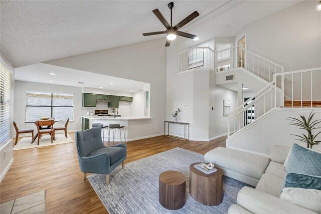 12910 Steeple Chase Dr, Austin, TX 78729 - living area featuring a ceiling fan, stairway, light wood-style flooring, baseboards, and high vaulted ceiling