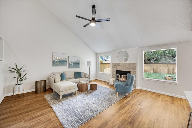 12910 Steeple Chase Dr, Austin, TX 78729 - living room with ceiling fan, a tiled fireplace, light wood finished floors, baseboards, and high vaulted ceiling