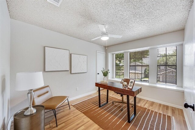 12910 Steeple Chase Dr, Austin, TX 78729 - home office featuring wood finished floors, ceiling fan, baseboards, and a textured ceiling