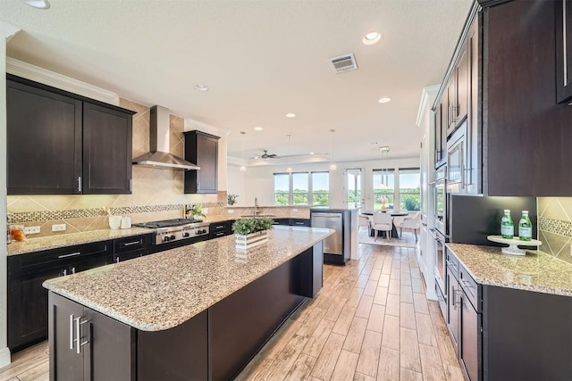 318 Fairway Ridge Rd, Georgetown, TX 78633 - kitchen with wall chimney range hood, a peninsula, a center island, light stone counters, and backsplash
