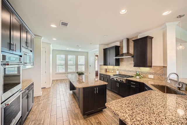 318 Fairway Ridge Rd, Georgetown, TX 78633 - kitchen featuring wall chimney range hood, a sink, appliances with stainless steel finishes, crown molding, and light stone counters