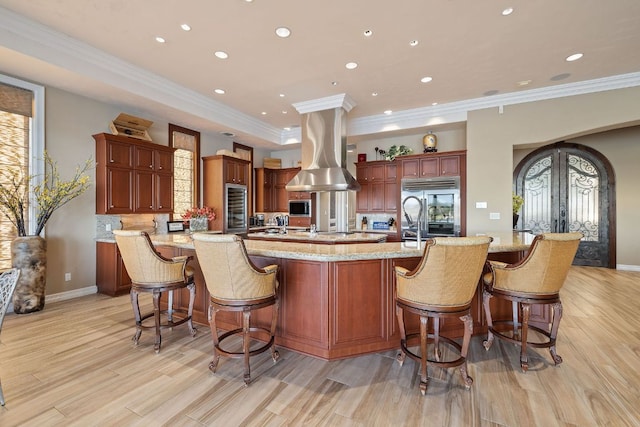 101 Matern Ct, Horseshoe Bay, TX 78657 - kitchen featuring high end fridge, island exhaust hood, crown molding, beverage cooler, and light wood-style floors