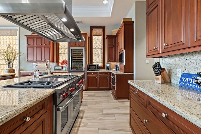 101 Matern Ct, Horseshoe Bay, TX 78657 - kitchen featuring wall chimney range hood, range with two ovens, beverage cooler, crown molding, and light stone countertops