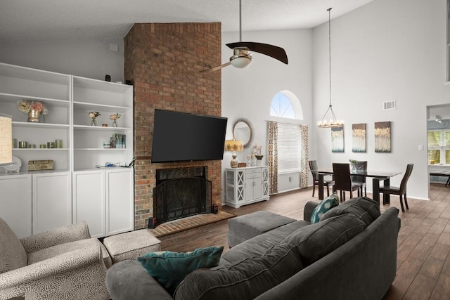 4019 Iriona Bnd, Austin, TX 78749 - living room with high vaulted ceiling, ceiling fan, wood finished floors, a fireplace, and a chandelier