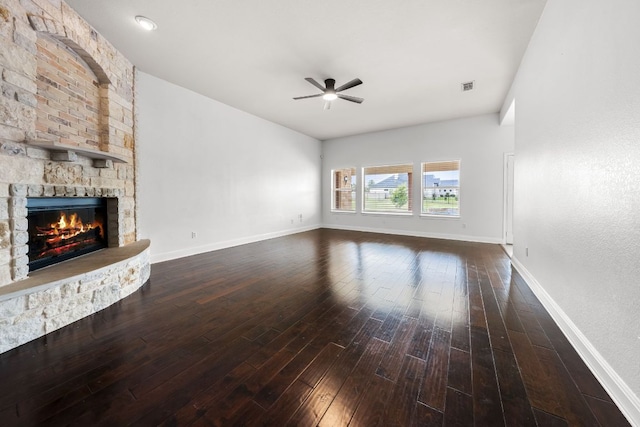 110 Starlight Trl, Georgetown, TX 78633 - unfurnished living room featuring ceiling fan, dark wood-style floors, a stone fireplace, and baseboards
