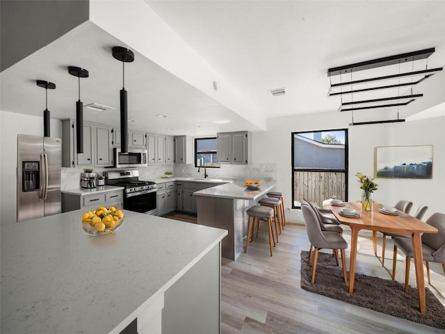 3912 Hillside Dr, Round Rock, TX 78681 - kitchen with stainless steel appliances, gray cabinetry, a peninsula, light countertops, and backsplash