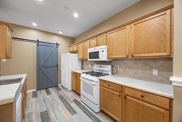 3817 Blue Mountain Path, Round Rock, TX 78681 - kitchen featuring white appliances, light wood-style flooring, backsplash, a barn door, and light countertops