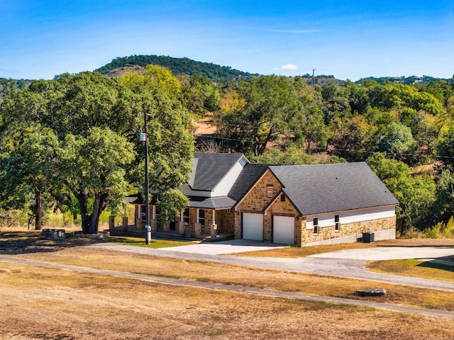 310 Shayla Ln, Canyon Lake, TX 78133 - view of front of property with stone siding, driveway, an attached garage, and a forest view