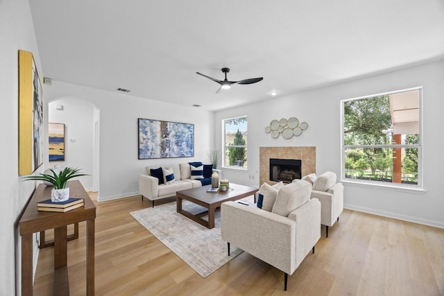 20420 Kearney Hill Rd, Pflugerville, TX 78660 - living area featuring arched walkways, light wood-style floors, a tile fireplace, baseboards, and a ceiling fan