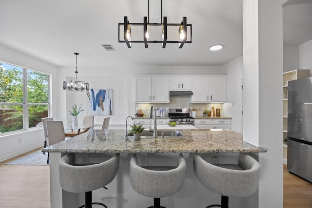 20420 Kearney Hill Rd, Pflugerville, TX 78660 - kitchen featuring a chandelier, appliances with stainless steel finishes, a sink, a breakfast bar area, and light wood finished floors