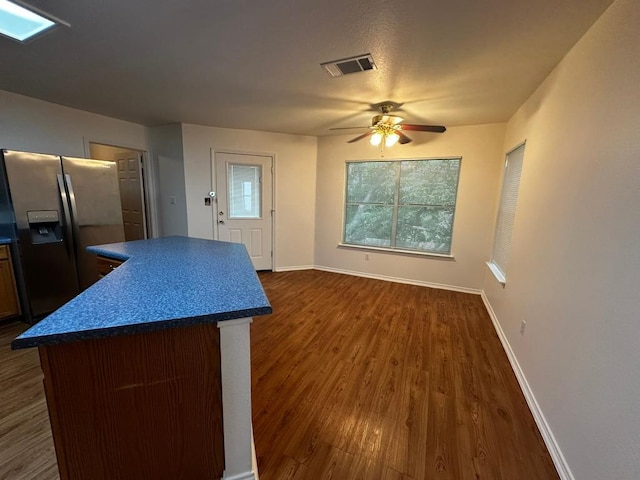 8429 Steamline Cir, Austin, TX 78745 - kitchen with stainless steel fridge with ice dispenser, dark countertops, ceiling fan, a kitchen island, and dark wood-style floors