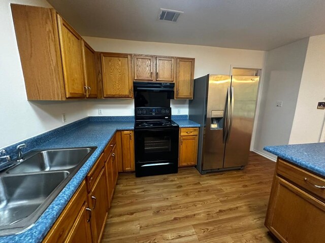 8429 Steamline Cir, Austin, TX 78745 - kitchen with stainless steel fridge with ice dispenser, black range oven, a sink, brown cabinets, and light wood-type flooring