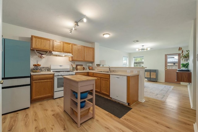 626 Goldenrod St, Kyle, TX 78640 - kitchen with white appliances, a peninsula, a sink, under cabinet range hood, and light wood finished floors