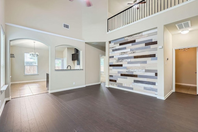 8521 White Ibis Dr, Austin, TX 78729 - unfurnished living room with hardwood / wood-style floors, a chandelier, a high ceiling, and arched walkways