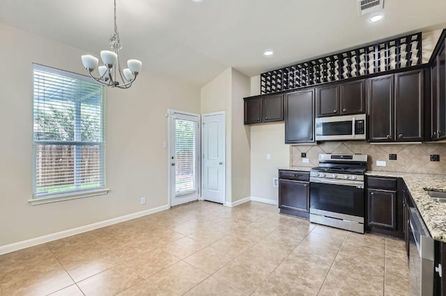 8521 White Ibis Dr, Austin, TX 78729 - kitchen with appliances with stainless steel finishes, light stone countertops, backsplash, a chandelier, and light tile patterned flooring