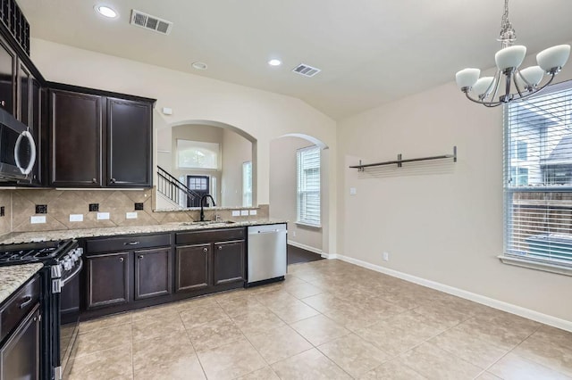 8521 White Ibis Dr, Austin, TX 78729 - kitchen with stainless steel appliances, arched walkways, tasteful backsplash, a chandelier, and vaulted ceiling
