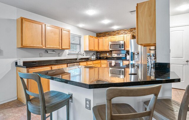 8936 Milton Lease Dr, Austin, TX 78747 - kitchen featuring appliances with stainless steel finishes, a breakfast bar, light brown cabinetry, and a sink