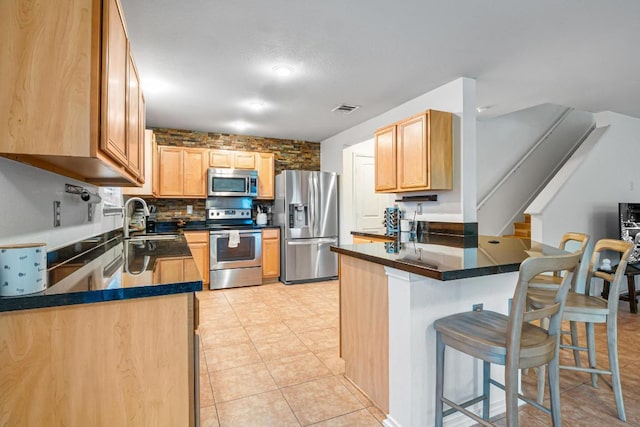 8936 Milton Lease Dr, Austin, TX 78747 - kitchen featuring appliances with stainless steel finishes, a sink, a peninsula, dark countertops, and a kitchen breakfast bar