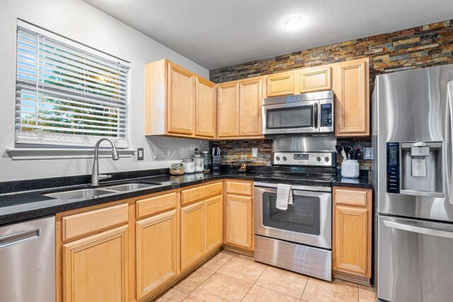 8936 Milton Lease Dr, Austin, TX 78747 - kitchen featuring stainless steel appliances, a sink, backsplash, light tile patterned flooring, and light brown cabinets