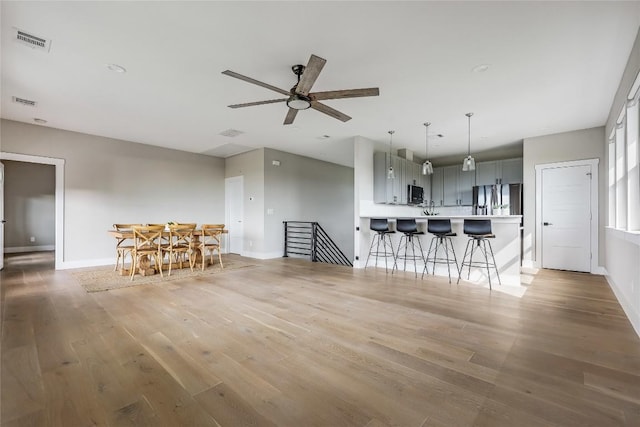 18700 Venture Dr, Point Venture, TX 78645 - kitchen featuring appliances with stainless steel finishes, gray cabinetry, a kitchen breakfast bar, ceiling fan, and light wood-style flooring