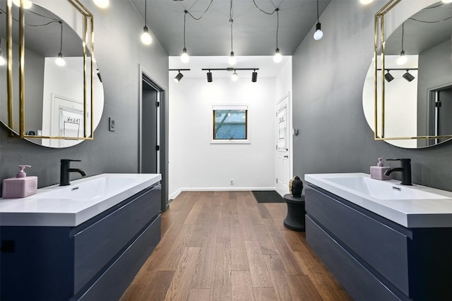525 Barton Blvd, Austin, TX 78704 - bathroom with two vanities, wood finished floors, rail lighting, and baseboards