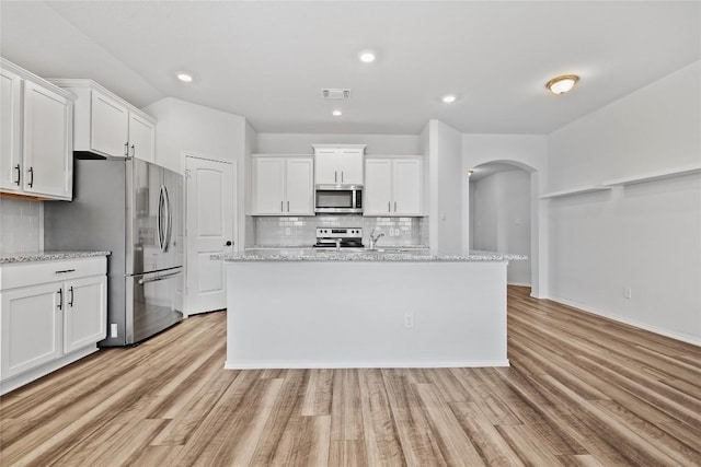 229 Reagor Dr, Taylor, TX 76574 - kitchen featuring appliances with stainless steel finishes, backsplash, arched walkways, white cabinetry, and recessed lighting