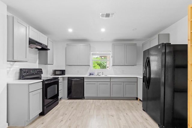 204 E Brenham St, Elgin, TX 78621 - kitchen with black appliances, under cabinet range hood, gray cabinetry, a sink, and recessed lighting