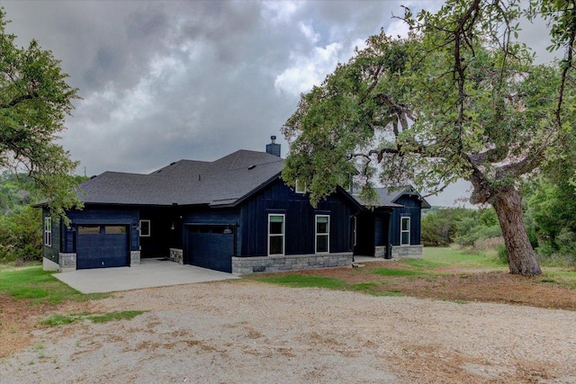 13401 Trail Driver, Austin, TX 78737 - rear view of house featuring dirt driveway, board and batten siding, a garage, a chimney, and stone siding