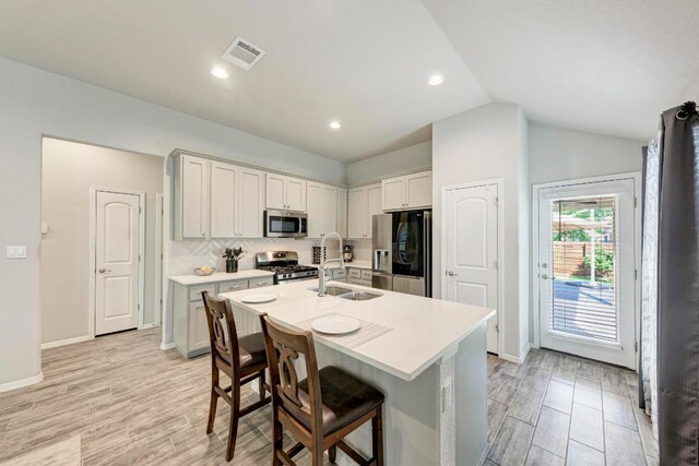 133 Free Stone Dr, Georgetown, TX 78628 - kitchen with stainless steel appliances, a sink, a kitchen island with sink, light countertops, and vaulted ceiling
