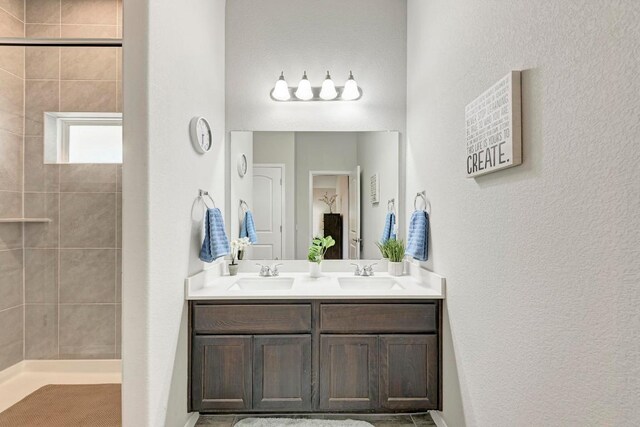 133 Free Stone Dr, Georgetown, TX 78628 - full bathroom featuring double vanity, a tile shower, and a textured wall