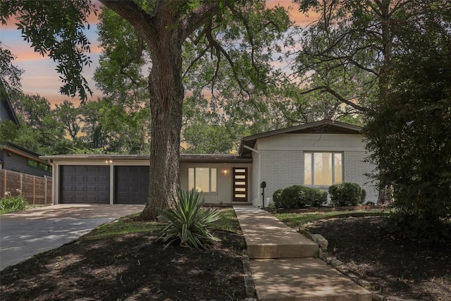 2322 Westoak Dr, Austin, TX 78704 - mid-century modern home featuring an attached garage, brick siding, and concrete driveway
