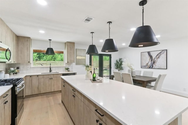 2322 Westoak Dr, Austin, TX 78704 - kitchen with stainless steel appliances, light brown cabinetry, light wood finished floors, light countertops, and recessed lighting