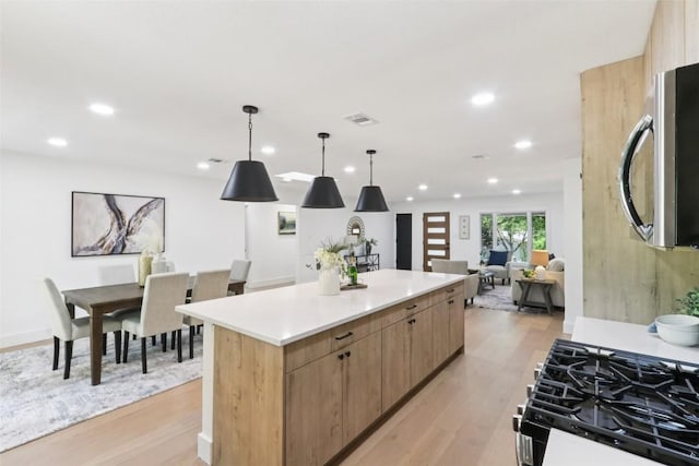 2322 Westoak Dr, Austin, TX 78704 - kitchen with appliances with stainless steel finishes, a kitchen island, recessed lighting, light wood-style flooring, and light countertops