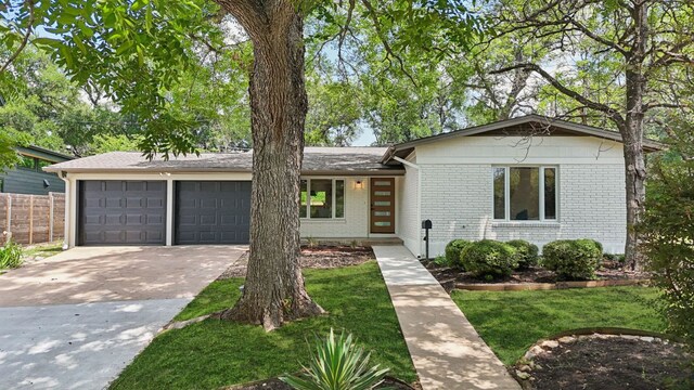 2322 Westoak Dr, Austin, TX 78704 - view of front facade featuring an attached garage, brick siding, and driveway
