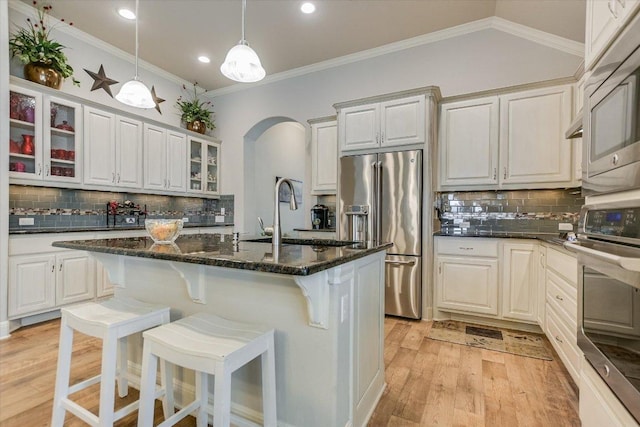 2416 Montello Ct, Leander, TX 78641 - kitchen featuring stainless steel appliances, arched walkways, backsplash, light wood-style floors, and glass insert cabinets