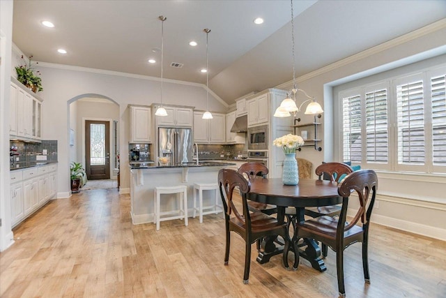 2416 Montello Ct, Leander, TX 78641 - dining space with arched walkways, ornamental molding, light wood finished floors, recessed lighting, and lofted ceiling