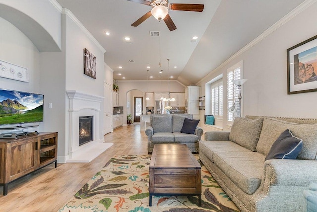 2416 Montello Ct, Leander, TX 78641 - living area featuring ceiling fan, ornamental molding, light wood-style floors, arched walkways, and a glass covered fireplace