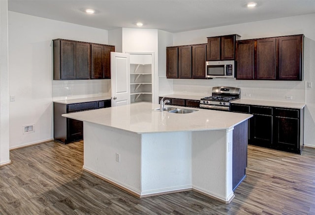 102 George Kimble Cv, Bastrop, TX 78602 - kitchen featuring stainless steel appliances, a sink, wood finished floors, tasteful backsplash, and a kitchen island with sink
