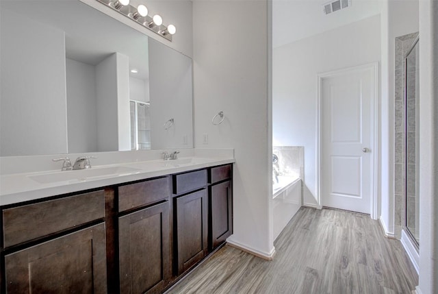 102 George Kimble Cv, Bastrop, TX 78602 - bathroom with wood finished floors, a stall shower, a garden tub, double vanity, and baseboards