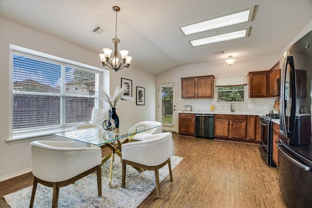 11120 Los Comancheros Rd, Austin, TX 78717 - dining room with wood finished floors, a chandelier, vaulted ceiling, a skylight, and baseboards