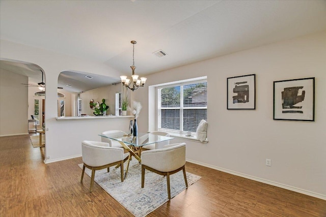 11120 Los Comancheros Rd, Austin, TX 78717 - dining area featuring wood finished floors, arched walkways, a chandelier, baseboards, and vaulted ceiling