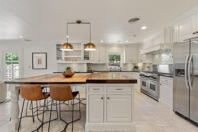 4607 Balcones Dr, Austin, TX 78731 - kitchen featuring stainless steel appliances, wood counters, white cabinets, decorative backsplash, and a center island
